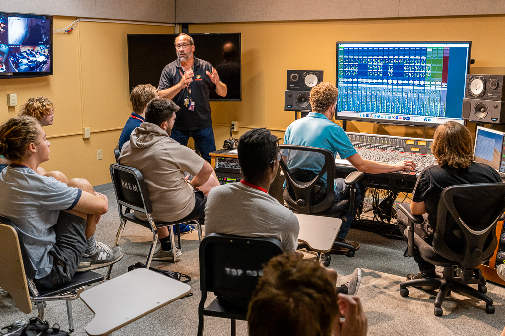 Students learn from professors in a music studio.