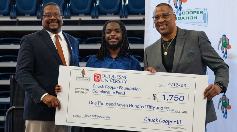 two men handing check to high school student