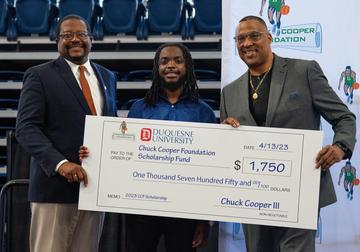 two men handing check to high school student
