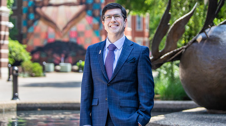 Dr. David Dausey standing outside on campus in a suit.