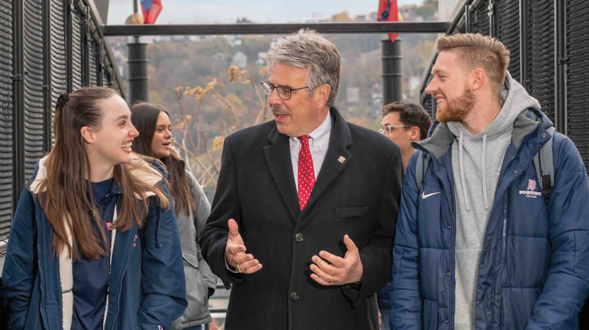 President Gormley walking on the bridge with students