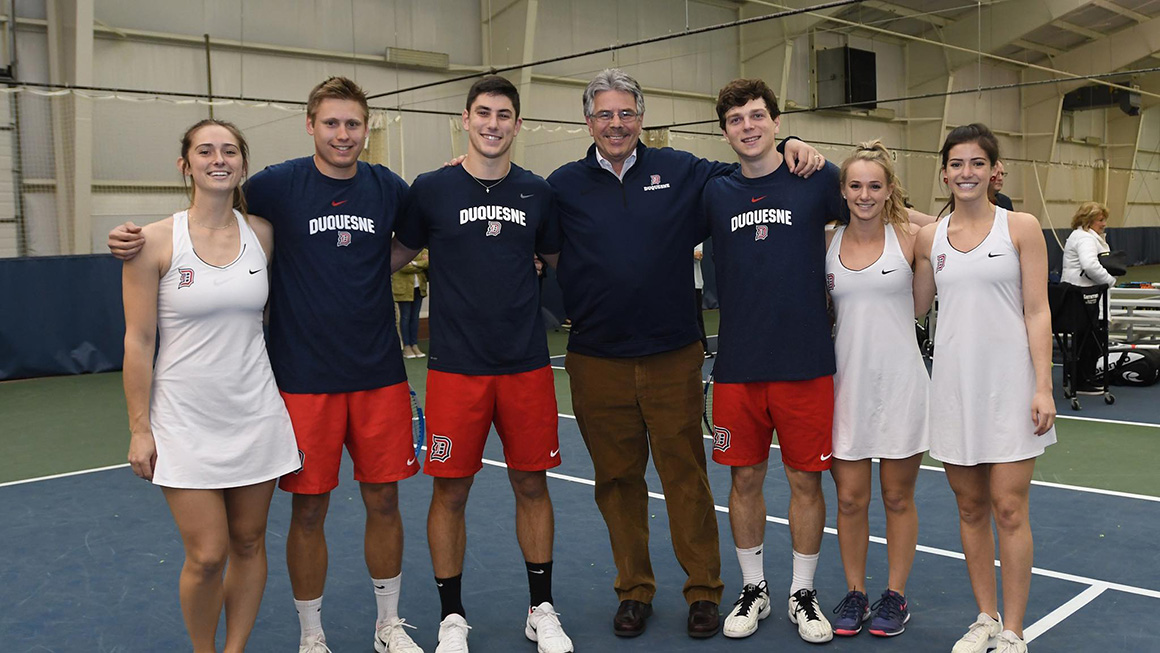 President posing with group of student athletes.