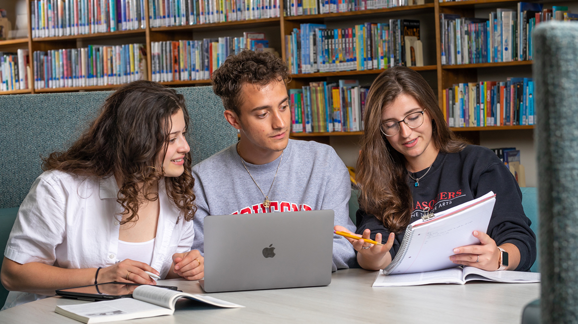 Duquesne students in library gathered around laptop