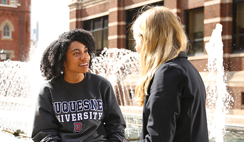 DU students talking at fountain in front of Canevin Hall.