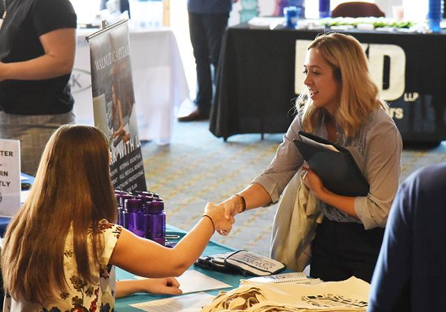 A female student shaking hands with a recruiter at a Career Fair.