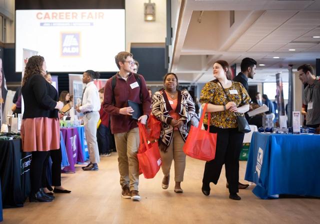 Three students walking through employer tables at the Career Fair