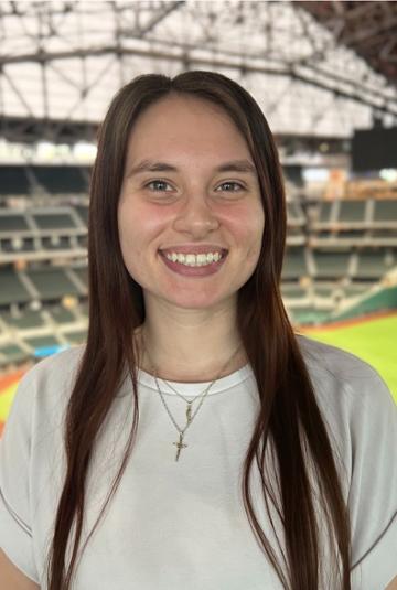 Photo of alumna Maria Doench with baseball field and stadium in the background.