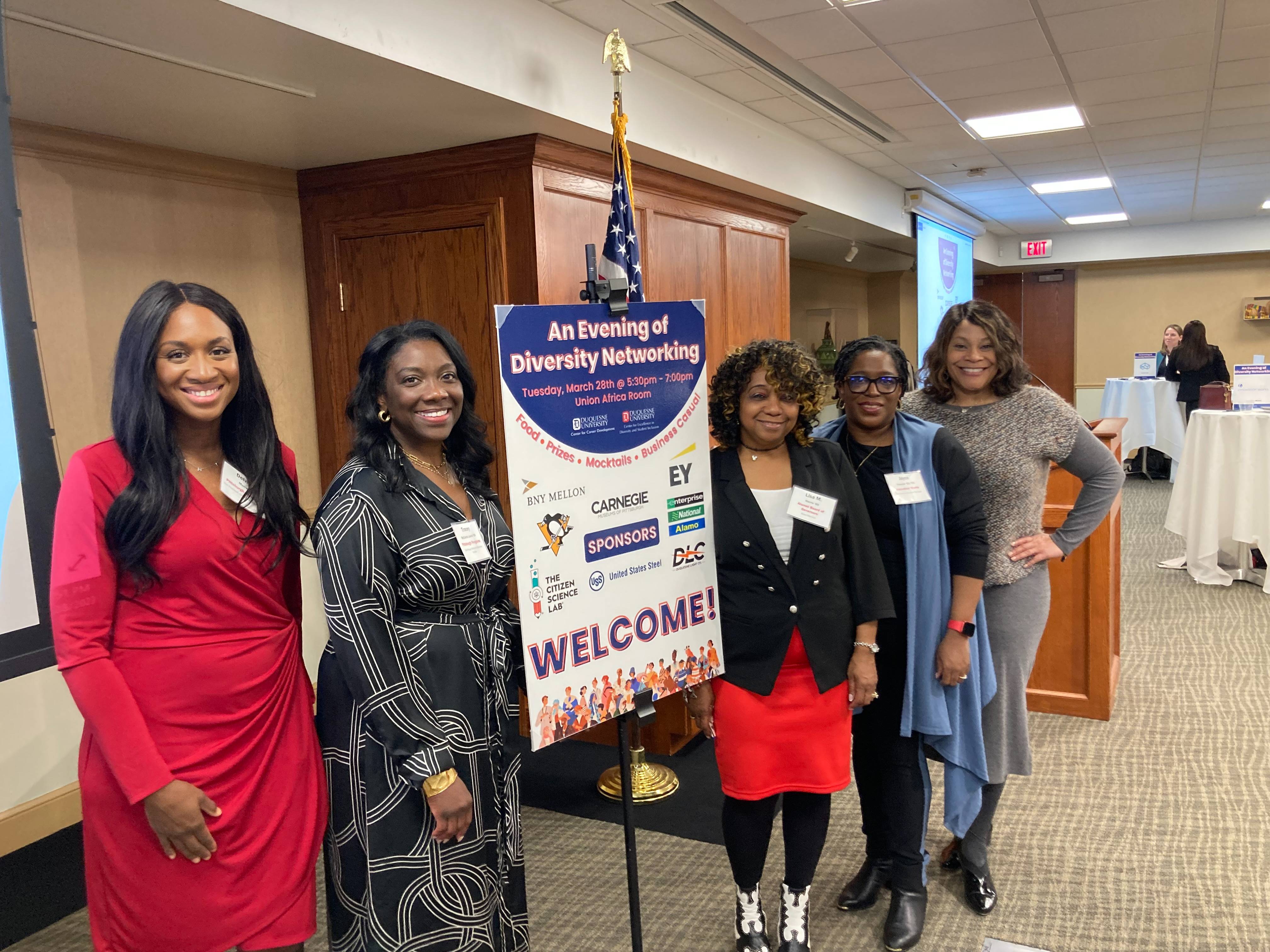 4 women standing next to welcome sign at a previous diversity in networking event