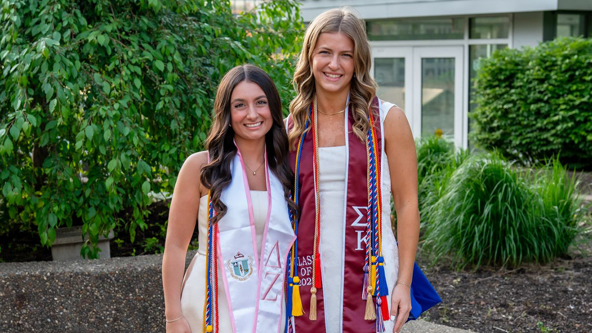 Marissa Panzetta and Sarah Martin outside of Rockwell Hall on graduation day.