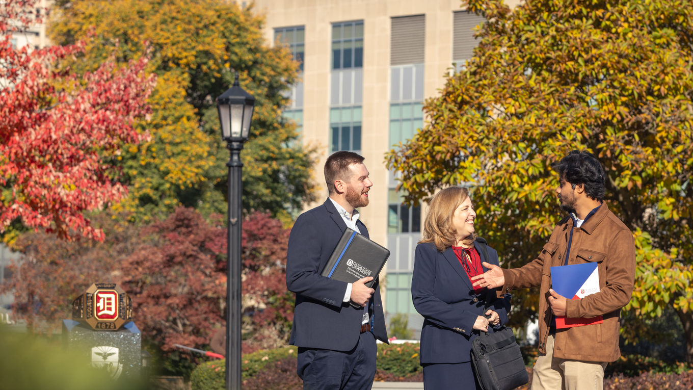 Three graduate students outside of Rockwell Hall in the fall.