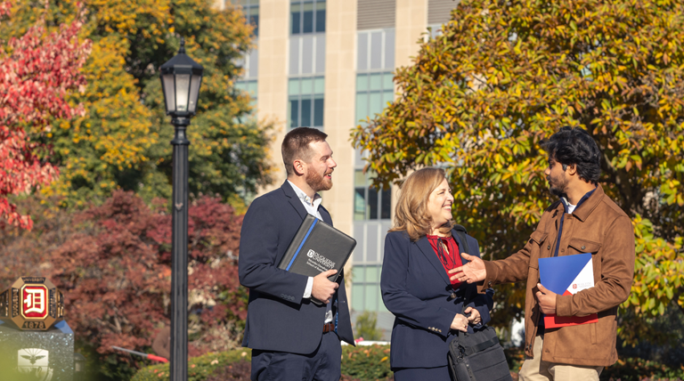 Three MBA students in the fall, outside of Rockwell Hall