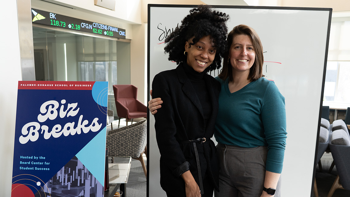 Success Coaches Shakeria Carter (left) and  Michelle Curry (right) handing out coffee  and donuts during a midterm BizBreak.
