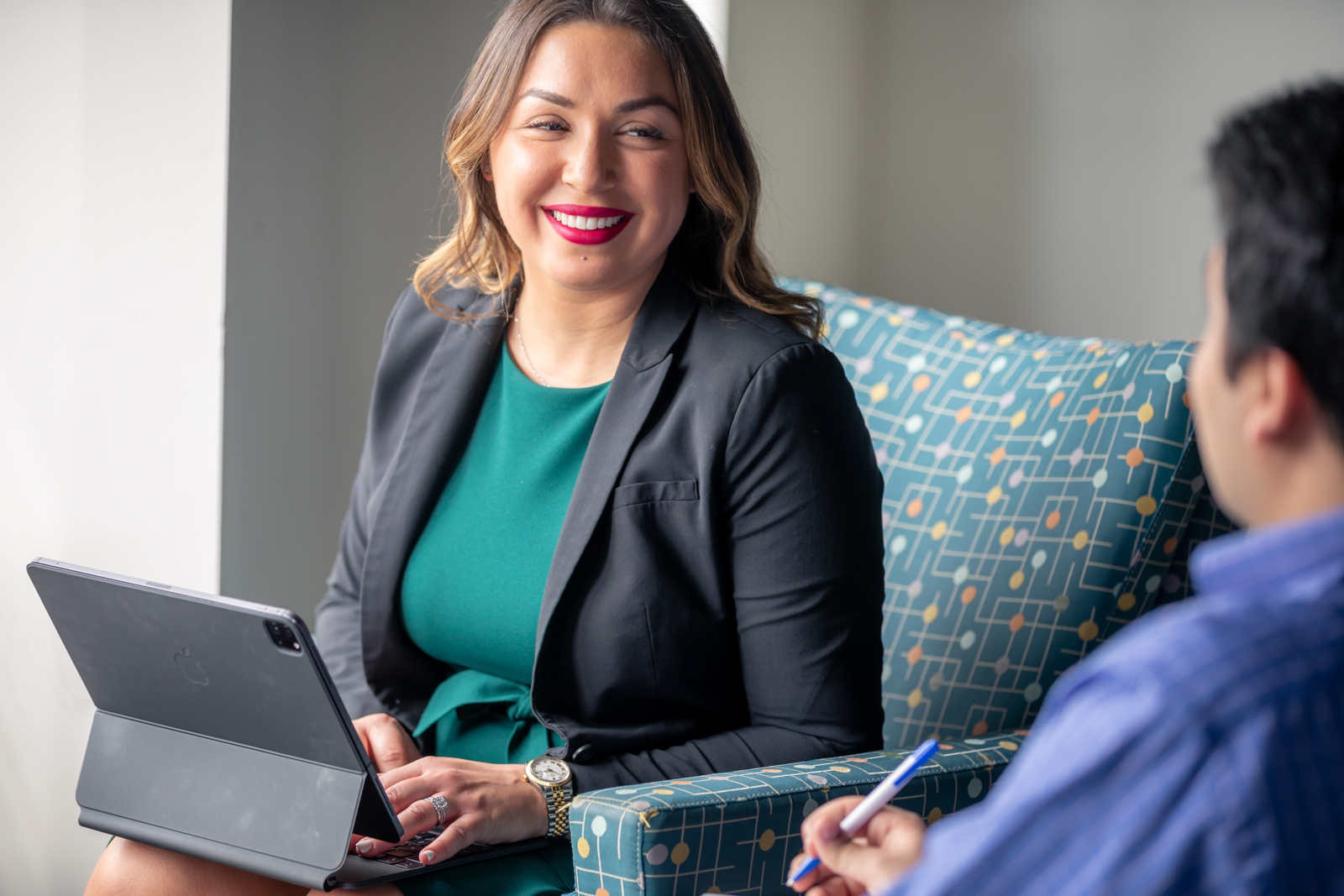 A graduate students sits with a laptop and smiles at her peers.