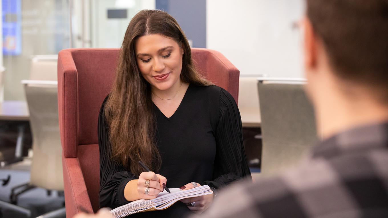 A student sits in a chair and diligently takes notes.