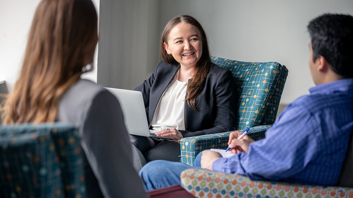 Three business students study and talk in a student lounge. 