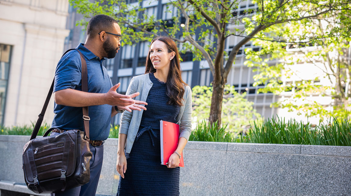 Two business students walk and talk in downtown Pittsburgh.