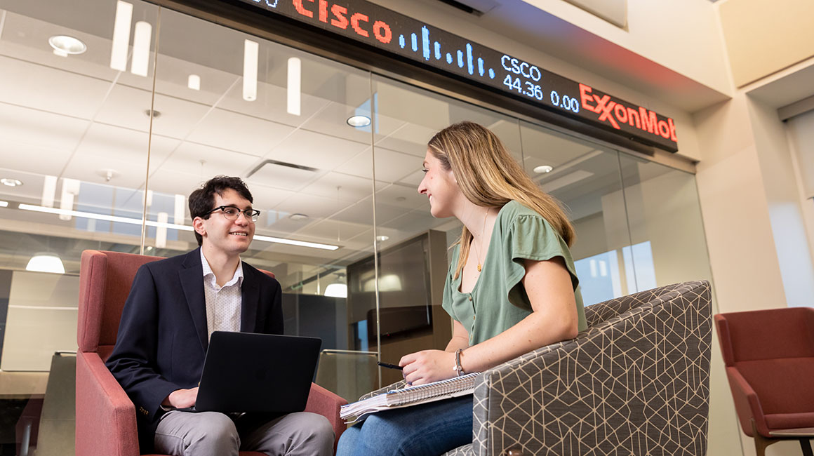 Two business sit and talk outside of the Investment Strategy Institute. 
