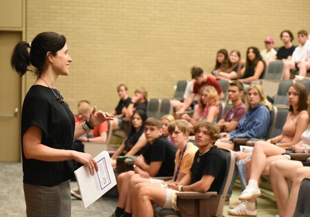a staff member smiles while speaking to a group of students