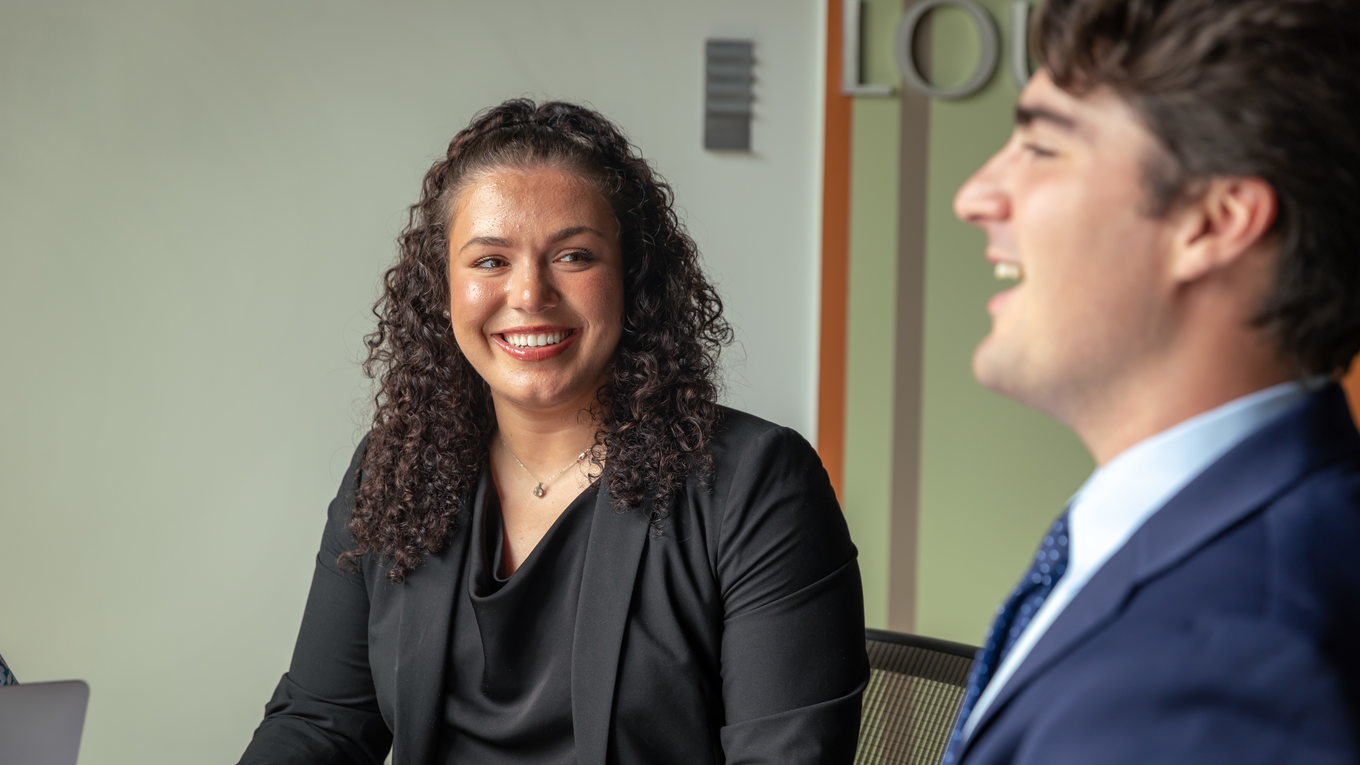A business law student smiles at her peer.