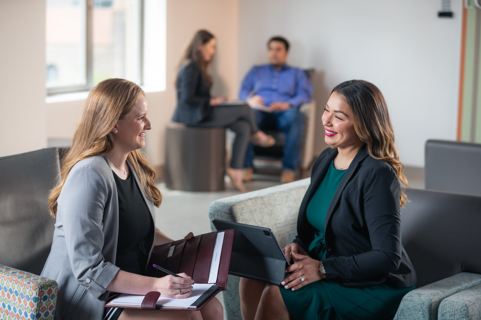 Two business students talk with other students in the background. 