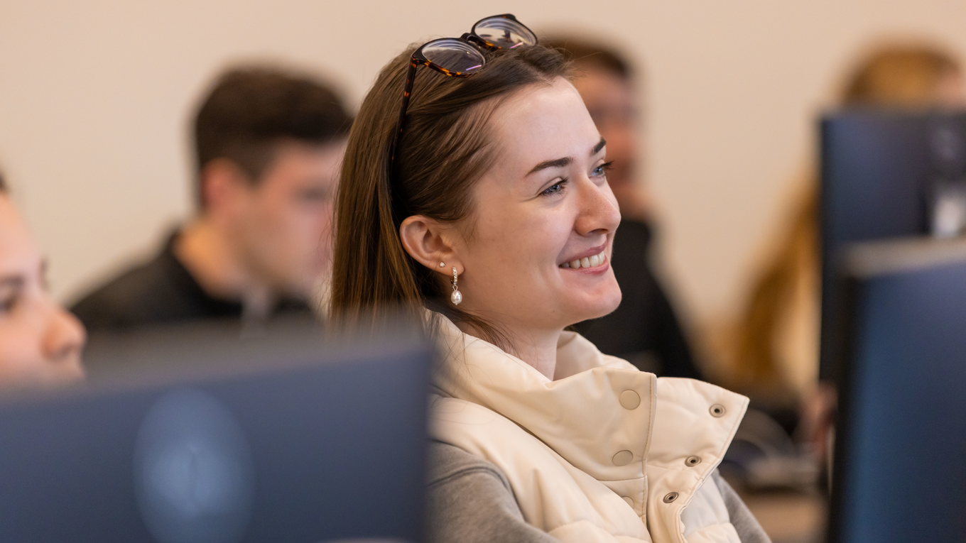 A student smiles in a computer lab.