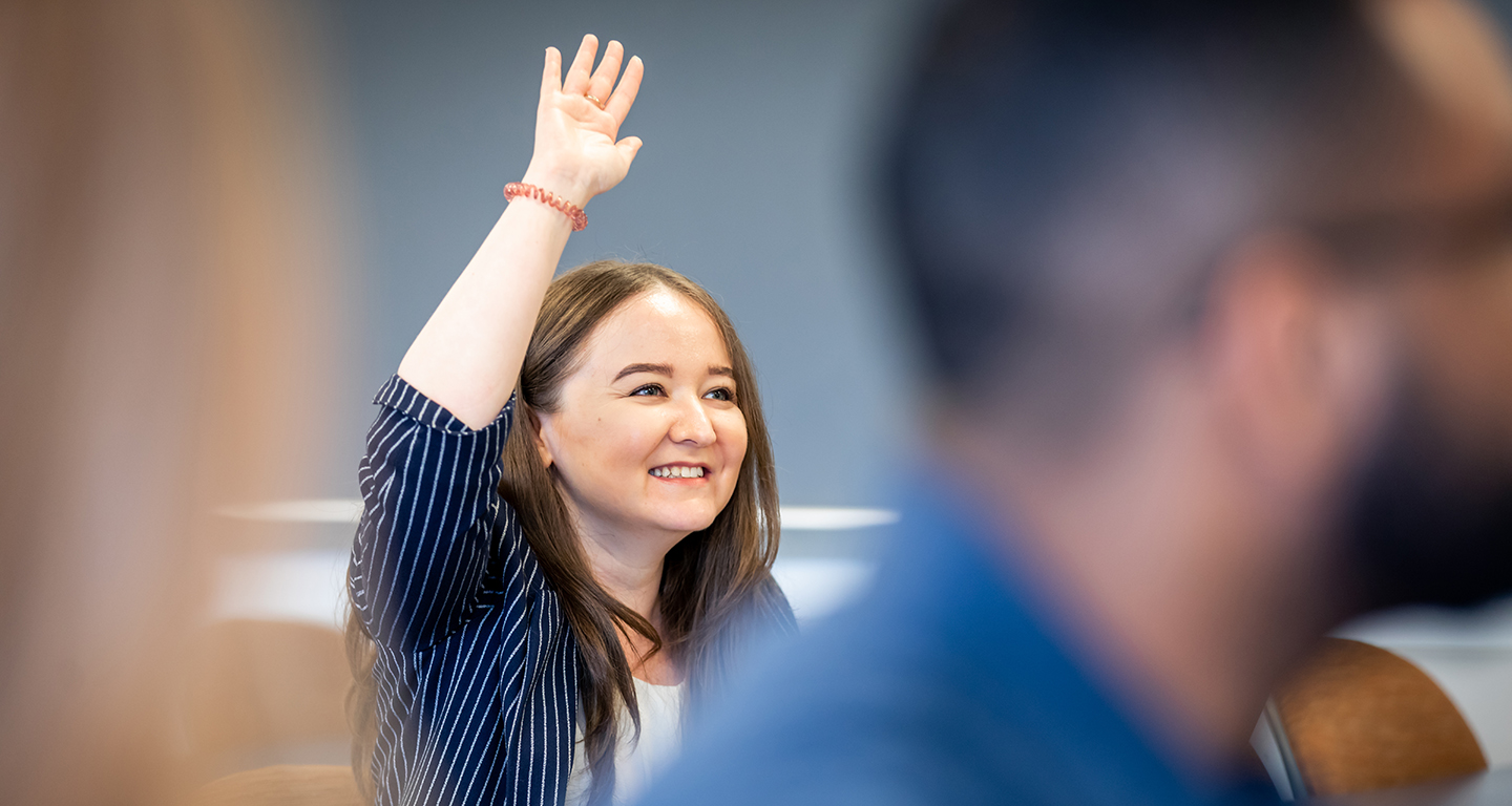 A business student raises her hand in class. 