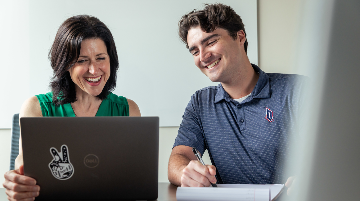 A student smiles as he works with an academic advisor.