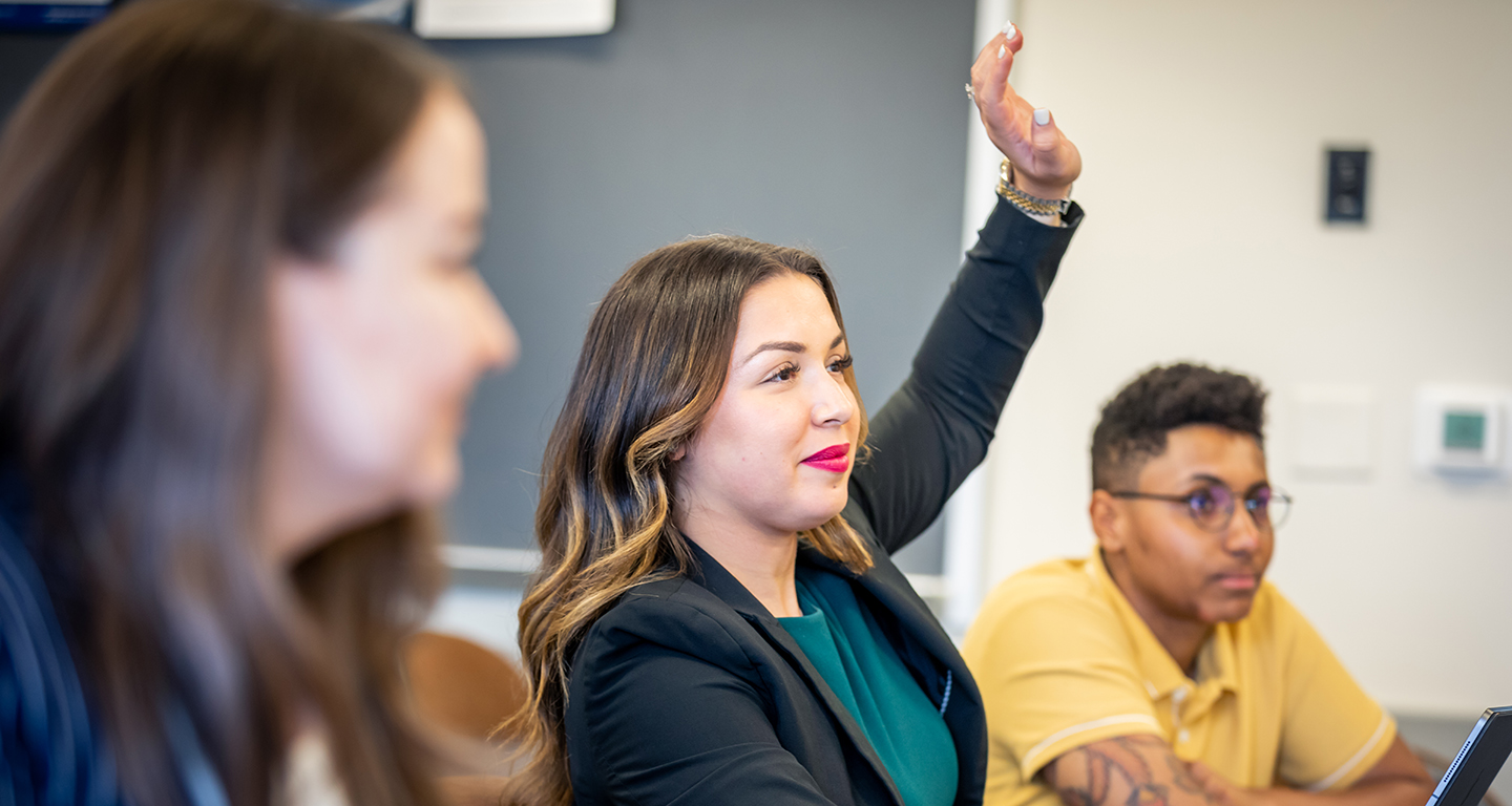 A business student raises her hand in class. 