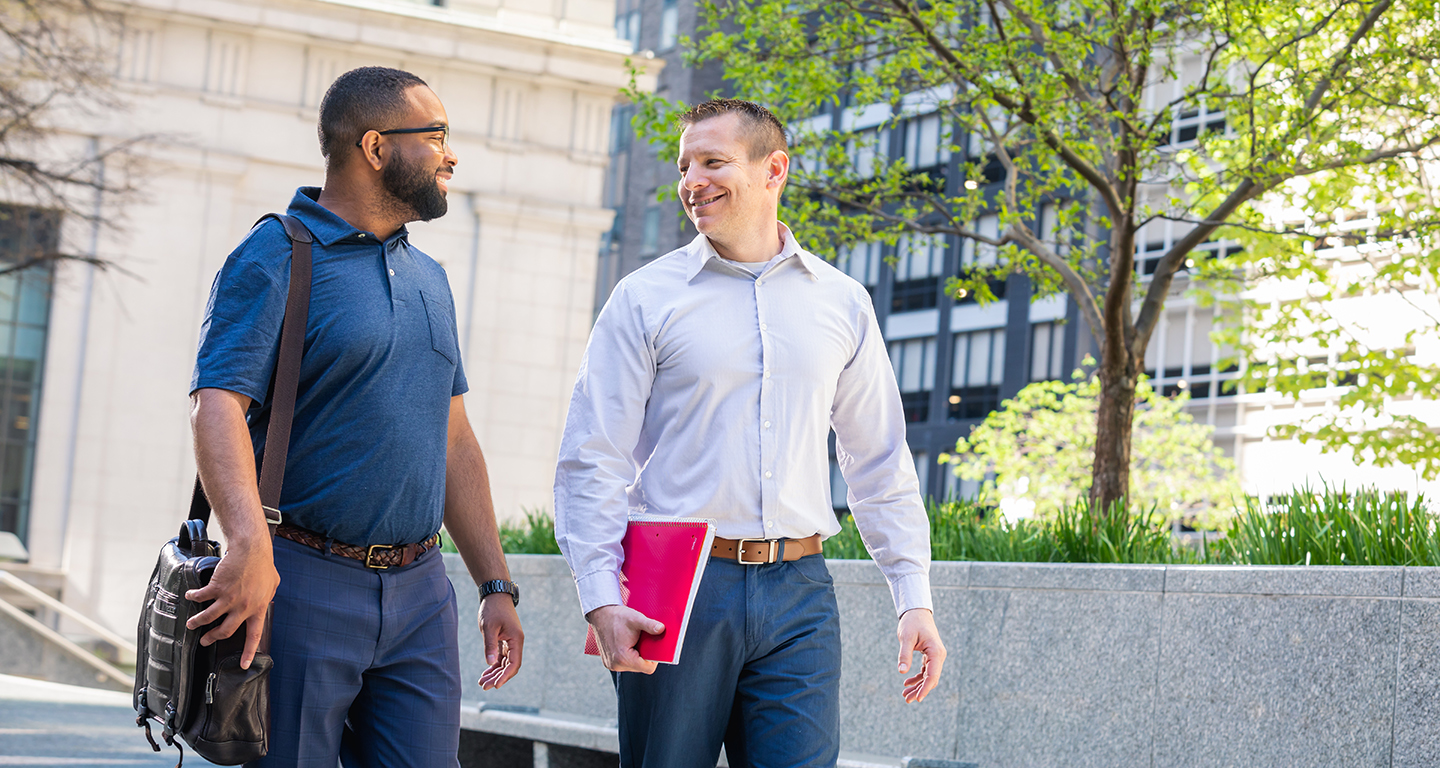Two business students walk and talk in downtown Pittsburgh. 