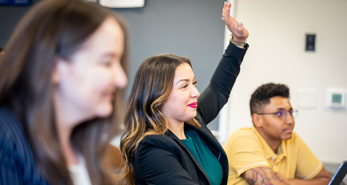 A business student raises her hand in class. 