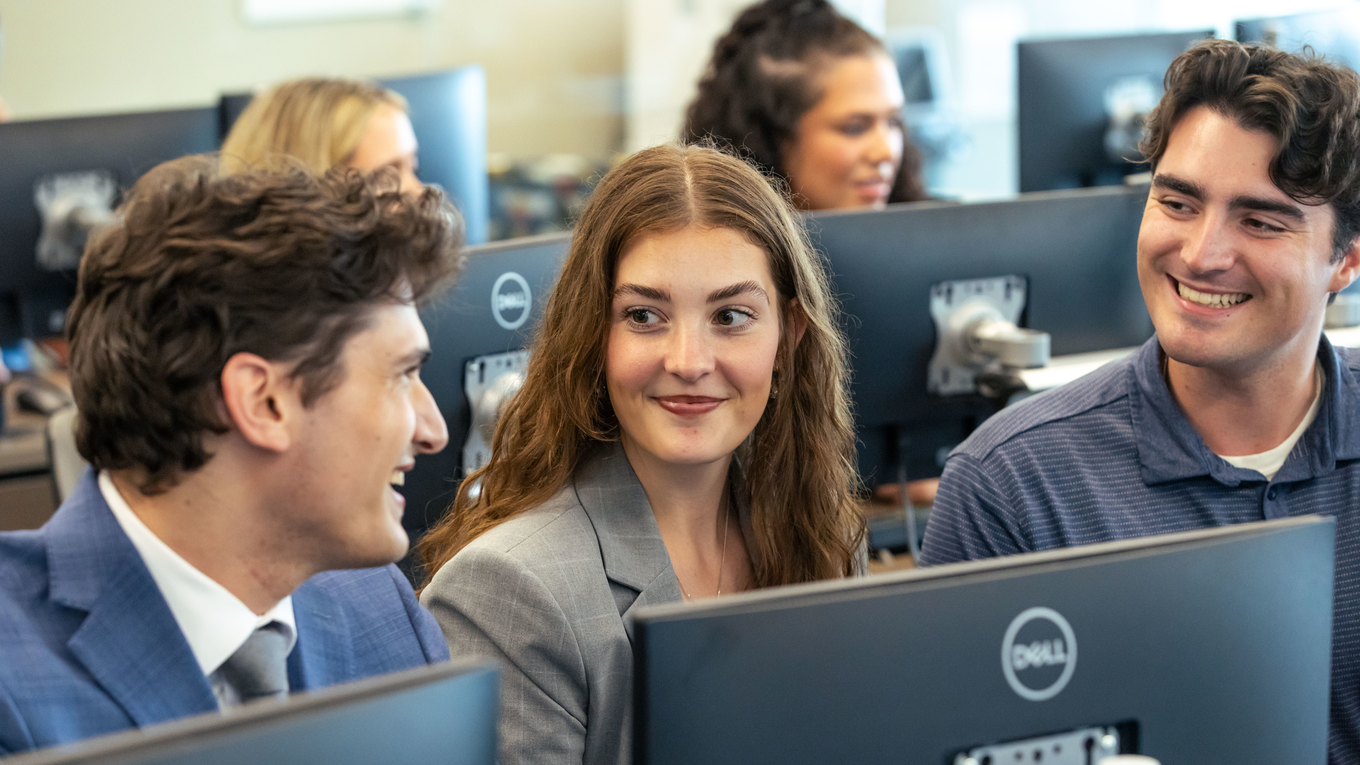 Students sitting in a computer lab, smiling.