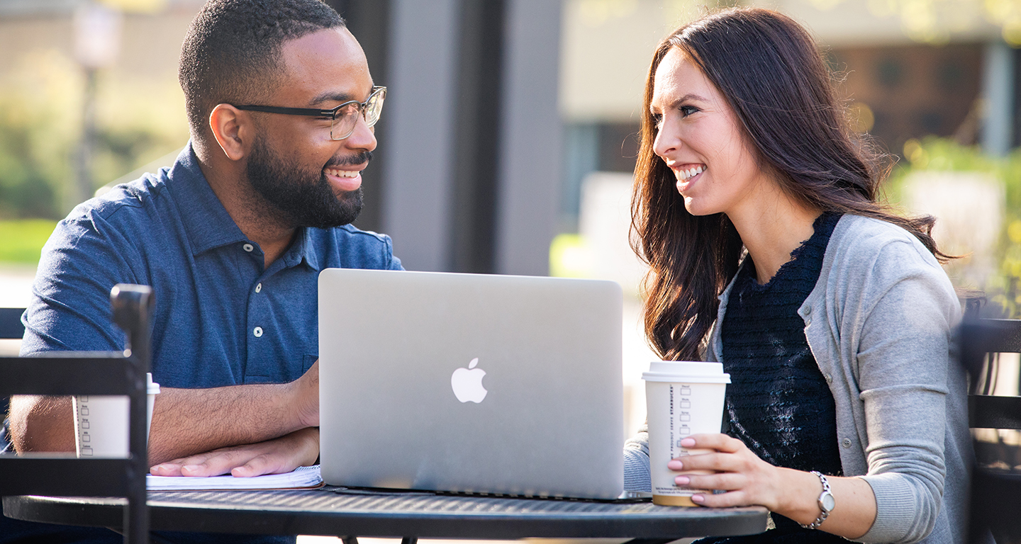 Two business students study outside. 