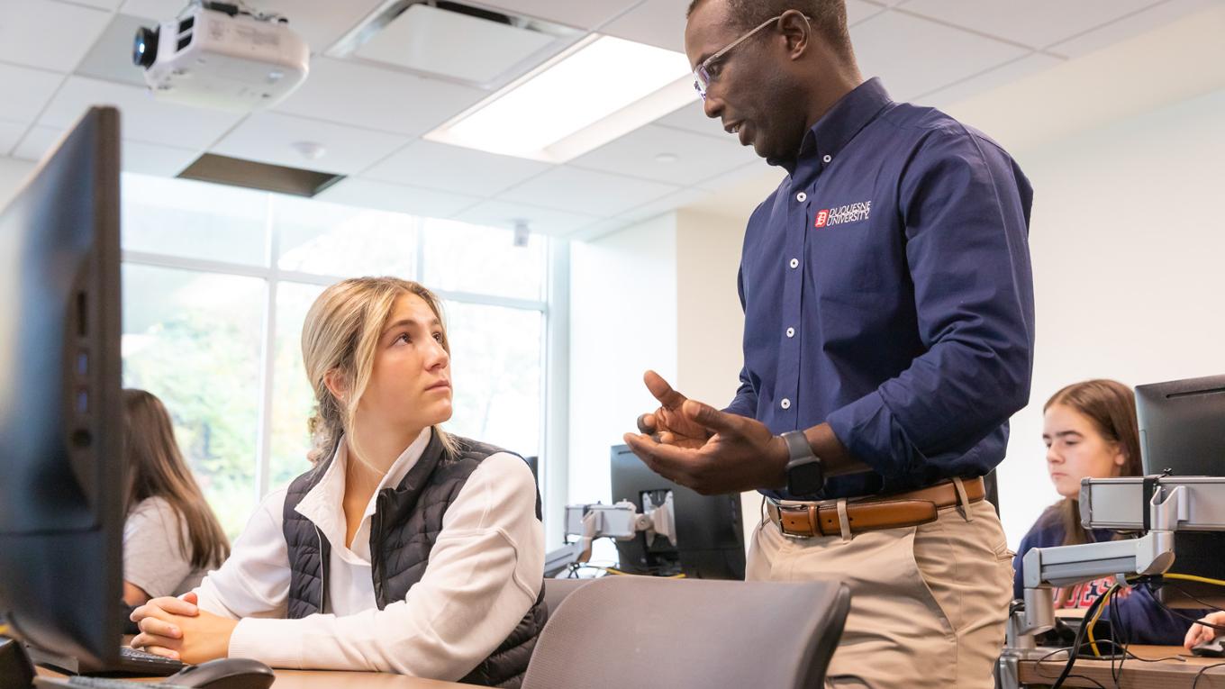 An information systems professor instructs a student.