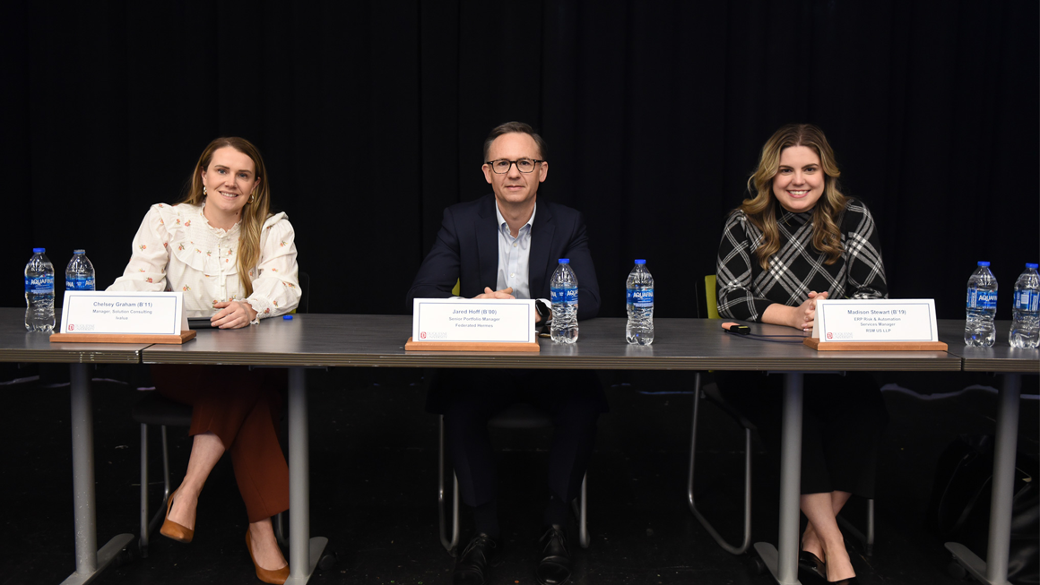 Alumni panelists pose on stage.