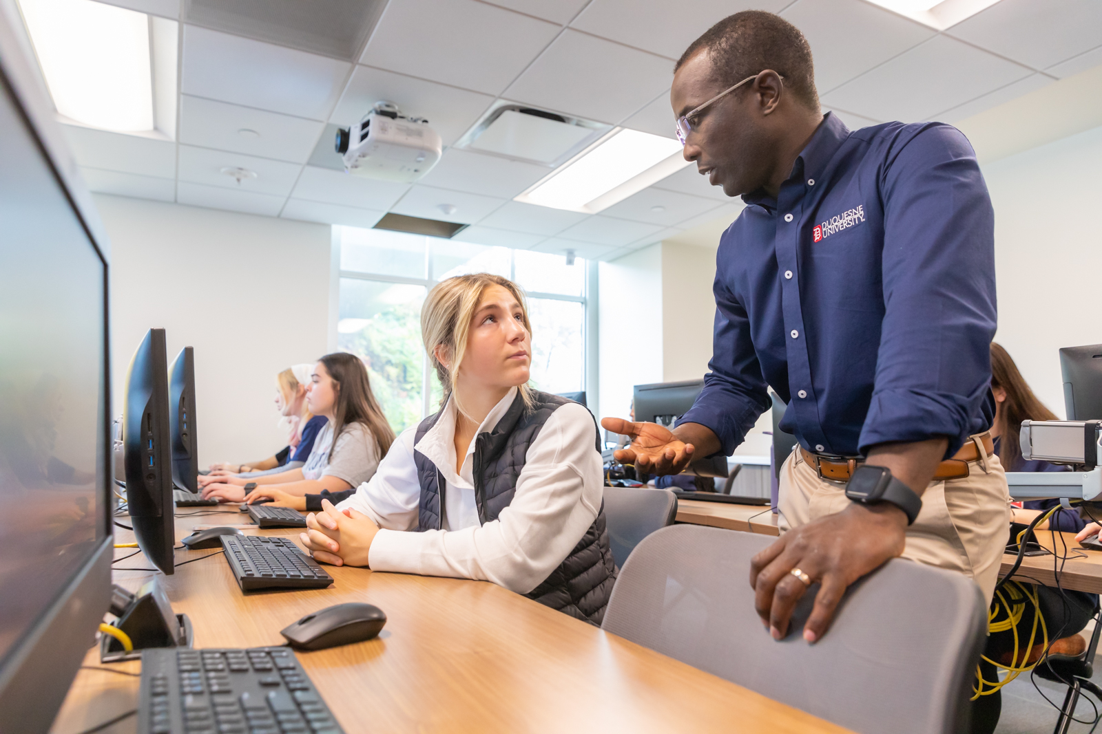 An instructor talks to a student in class. 