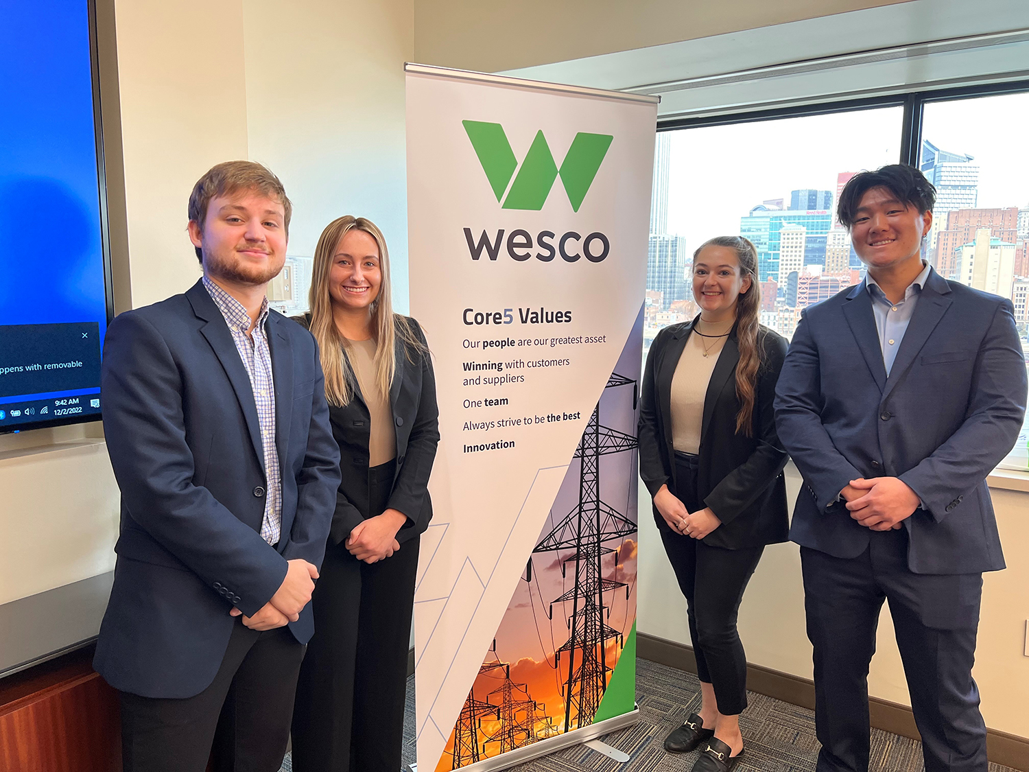 Four business students pose with a Wesco sign. 