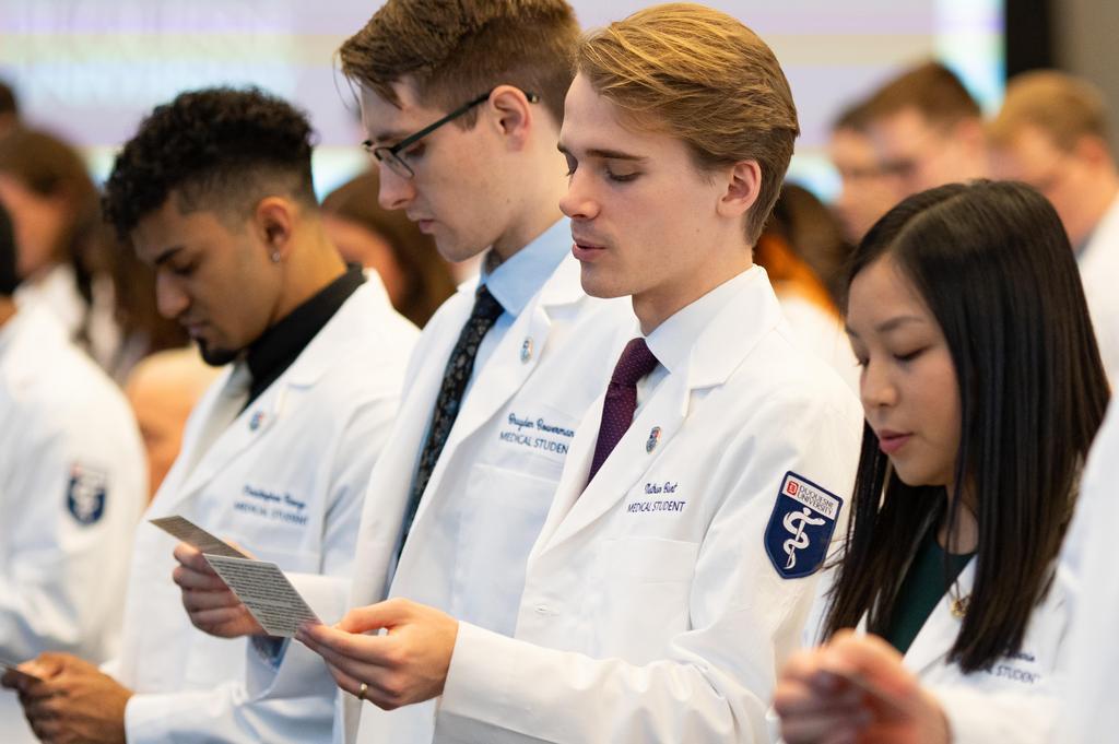 DUQCOM DO students taking oath at recent white coat ceremony.