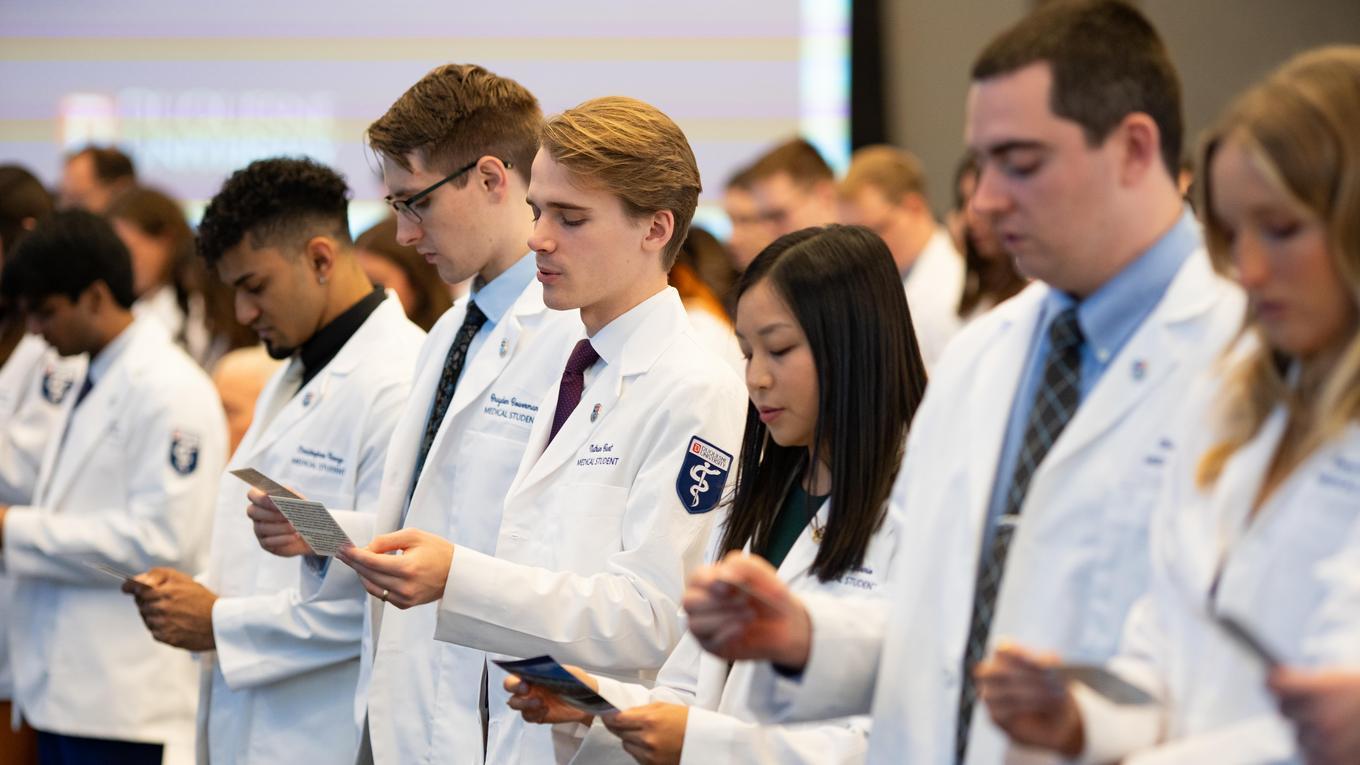 DUQCOM DO students taking oath at recent white coat ceremony.