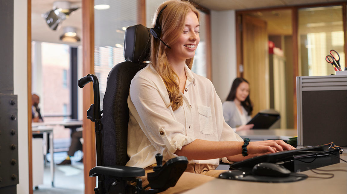 person with physical disability in high-tech wheelchair working at desk