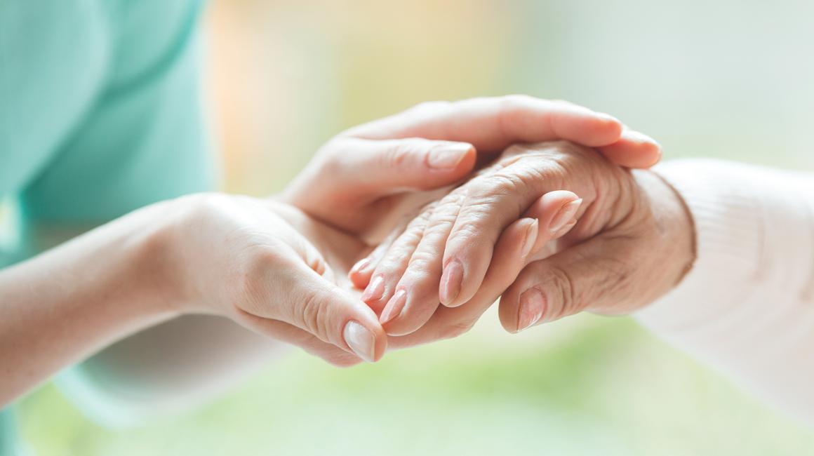 Health professional holding a patients hand.