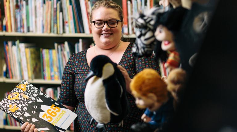 Duquesne student selecting penguin puppet and book in curriculum center