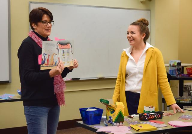 Dr. Carla Meyer reading children's book to class with Duquesne student next to her smiling and engaging