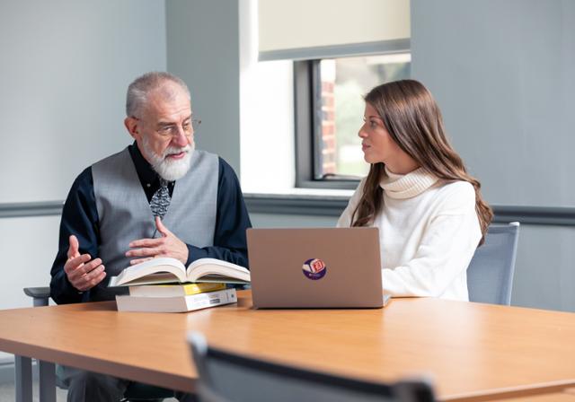 A professor gives a student a lesson in the classroom.