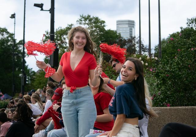 Two Duquesne student cheering with streamer amongst football crowd on Bluff