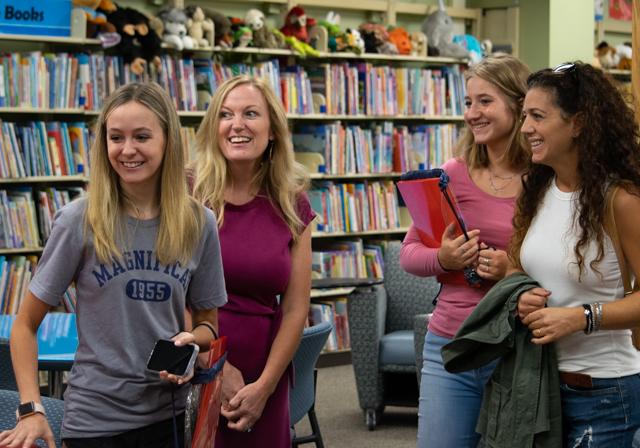 Mothers and daughters in campus library at FAST event smiling and coversing with folders and information in hand.