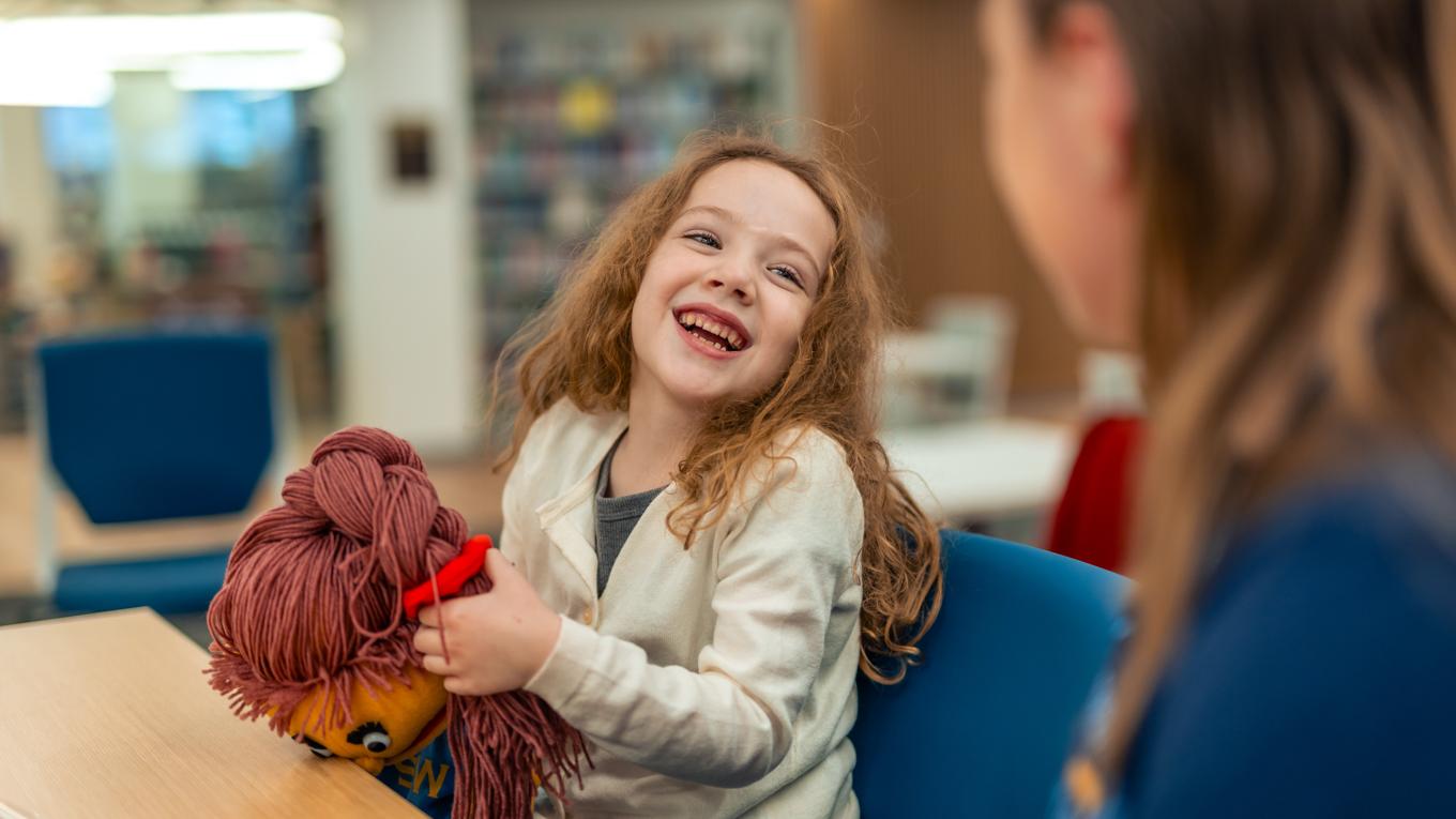 ABA Course Sequence for the BCBA Exam graduate in assessment as client smiles at her holding a puppet in a behavioral health session.