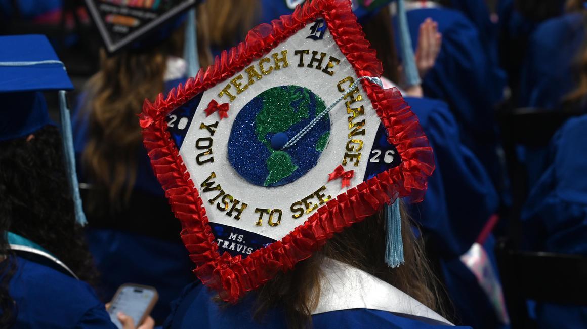 Education commencement graduates ready to make an impact dressed in regalia and decorated cap reading Teach the Change You Wish to See.