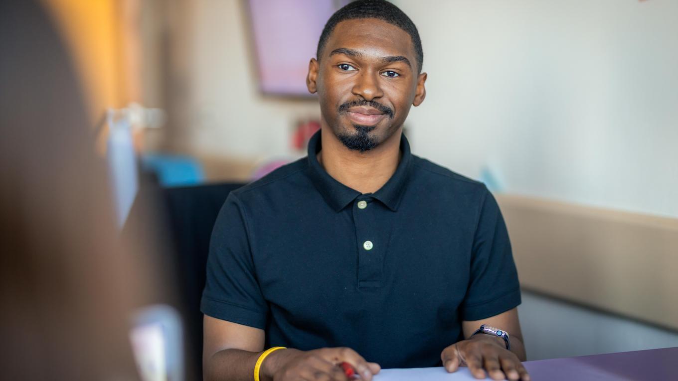M.S.Ed. School Supervision graduate student studying in Pittsburgh Pennsylvania classroom with notebook on desk listening to colleague