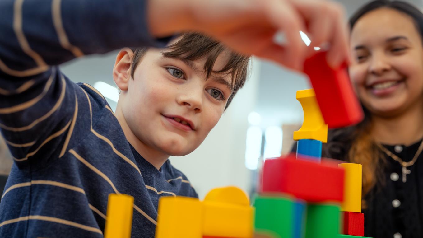 Student building colorful blocks in class with special education cognitive behavior physical health disabilities teacher Duquesne graduate.