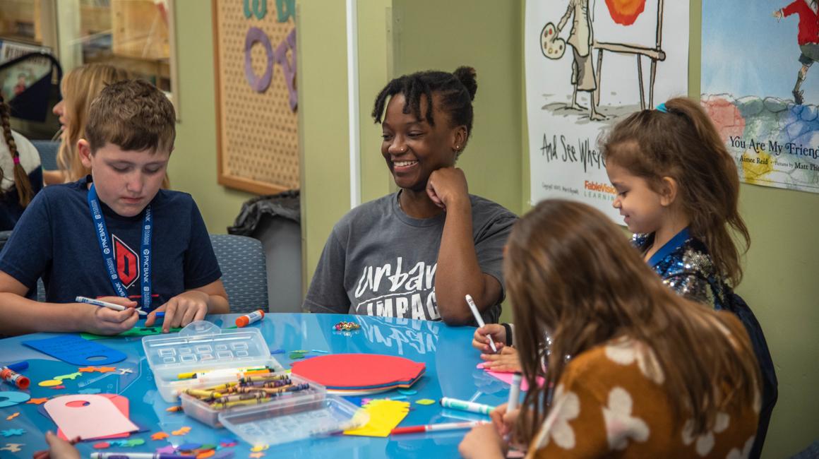 Duquesne student teacher with students in library curriculum center reading lessons